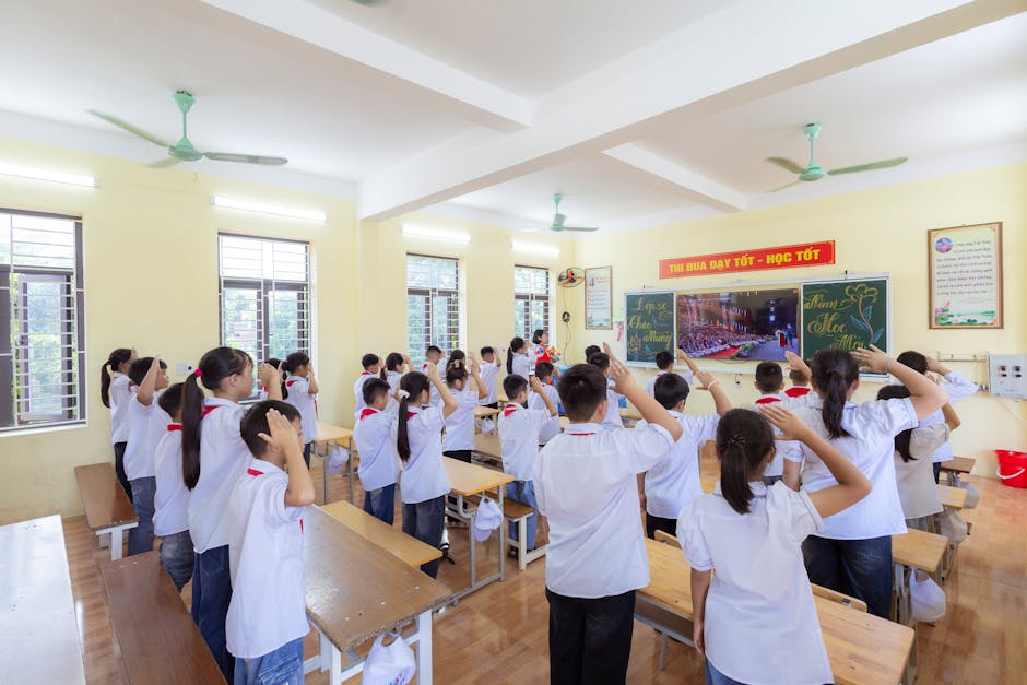 Students in uniforms saluting in a bright classroom during a school session